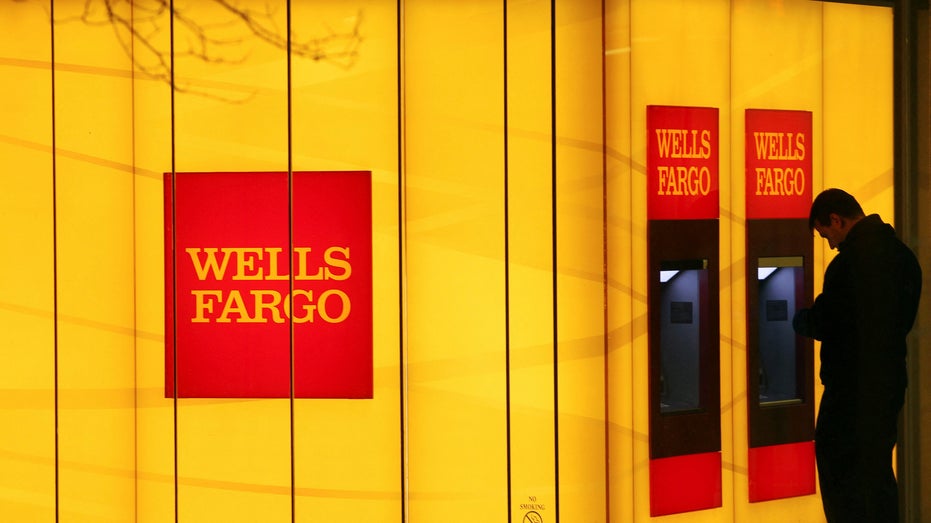 A man uses an automated teller machine (ATM) at a Wells Fargo Bank branch on a rainy morning in Washington